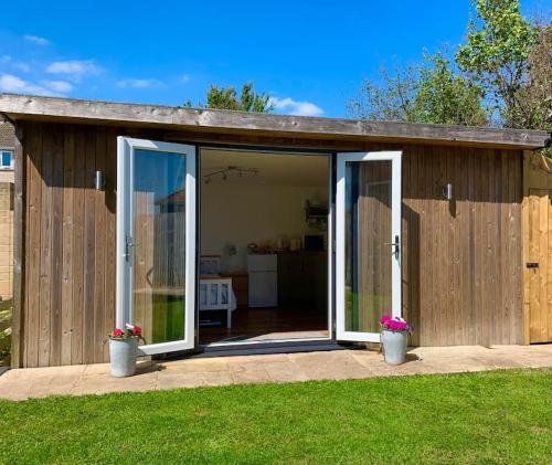 a small house with sliding glass doors in a yard at The Old Beauty Room in Paulton