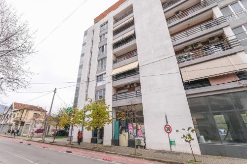 a tall white building on a city street at Two Steps Apartments Tirana in Tirana