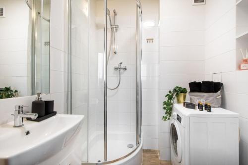 a bathroom with a shower and a sink and a washing machine at Apartments Centre by Arrenda in Warsaw