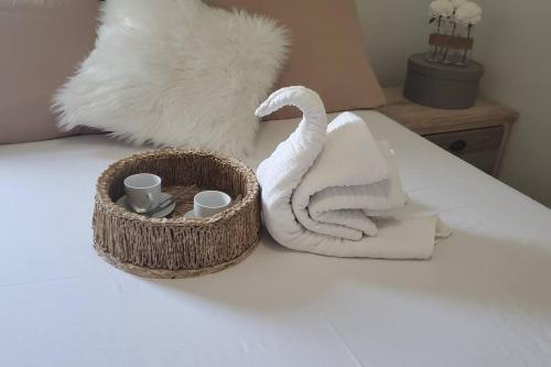 ein Handtuch und ein Korb mit Tassen und Handtüchern auf dem Bett in der Unterkunft Le Petit Saint-Barth in Baie-Mahault