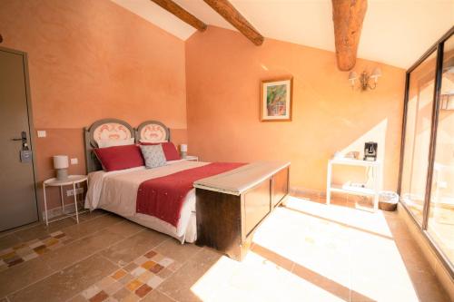 a bedroom with a large bed with a red blanket at Hôtel Le Mas des Grès & Restaurant Sous les Platanes in Lagnes