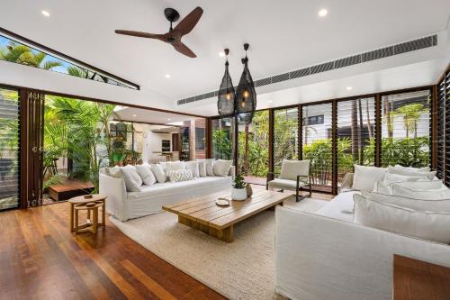 a living room with white furniture and large windows at Pavilion 5 in Byron Bay
