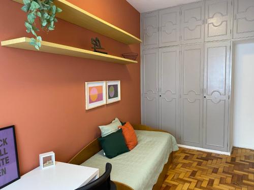 Dormitorio pequeño con cama y estante en Baixo Leblon com charme, lazer e home office, en Río de Janeiro
