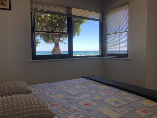 a bedroom with a bed and a window with the ocean at The Somerton Beach Retreat in Somerton Park