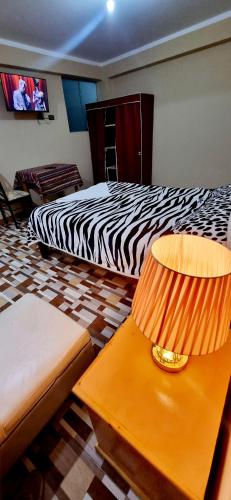 a bedroom with two beds and a table with a lamp at Hospedaje apus in Huaraz