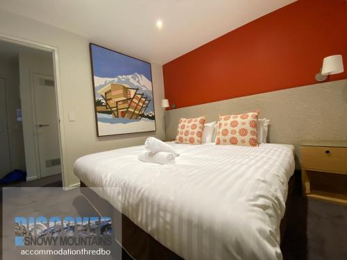 a bedroom with a large white bed with a painting on the wall at Snowman 1 in Thredbo