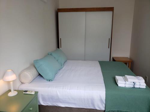 a bedroom with a bed with a blue pillow and a table at Apto beira-mar pé na areia in Barra Velha