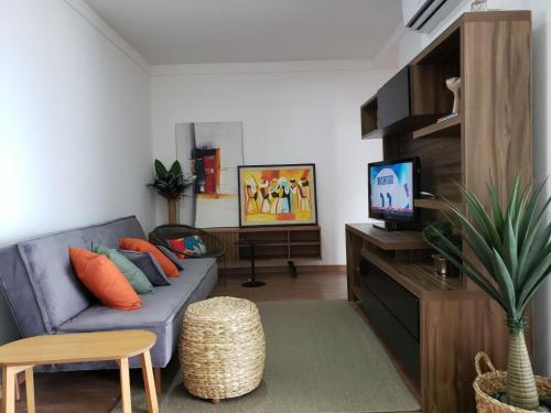 a living room with a blue couch and a tv at Apto beira-mar pé na areia in Barra Velha