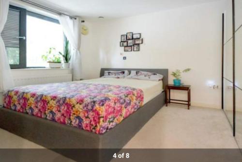 a bedroom with a large bed with a colorful blanket at London Holiday Home - Entire 4 Bedroom Private House with Kitchen, Living Room & private Garden - 1 Cape House London, Within 30 mins from Central London, London Bridge & Canary wharf in London