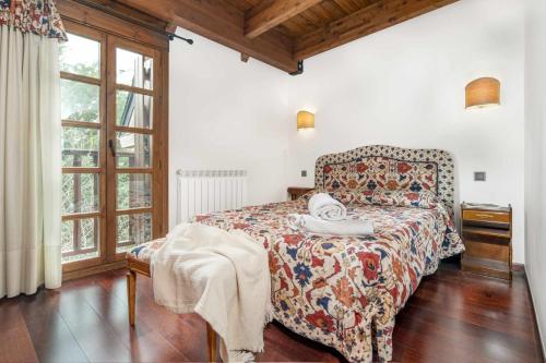 a bedroom with a bed with a floral bedspread and a window at Apartamento con las mejores vistas del valle in Sallent de Gállego