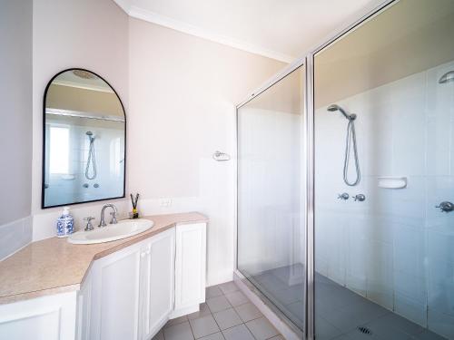 a white bathroom with a shower and a sink at 1-bedroom unit with balcony and ocean views! in Smiths Beach