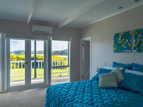 a bedroom with a blue bed and a balcony at 1-bedroom unit with balcony and ocean views! in Smiths Beach