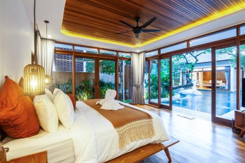 a bedroom with a large bed with a ceiling fan at Paya Paya Villa Seminyak in Seminyak
