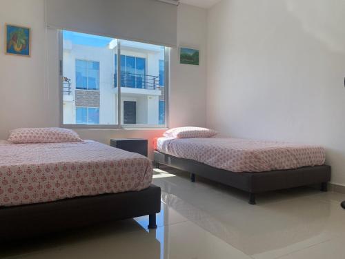 two beds in a room with a window at CASA VIA EL PEÑON in Girardot
