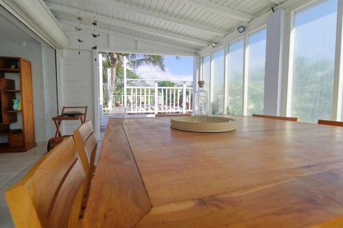 uma grande mesa de madeira num quarto com uma grande janela em Villa bord de mer au Moule em Le Moule