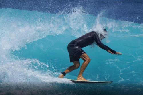 um homem a surfar uma onda numa prancha de surf no oceano em Villa bord de mer au Moule em Le Moule