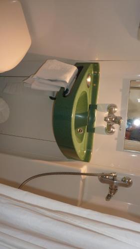 La salle de bains est pourvue d'un lavabo et d'un distributeur de savon vert. dans l'établissement Hôtel Eco Relais - Pau Nord, à Lons