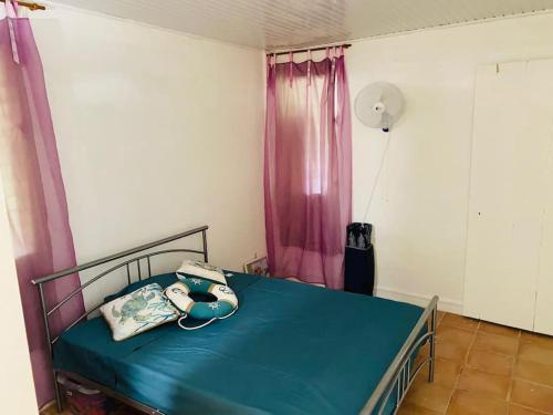 a bedroom with a bed with a blue sheet and a phone at Villa VICTORIA in Le Lamentin