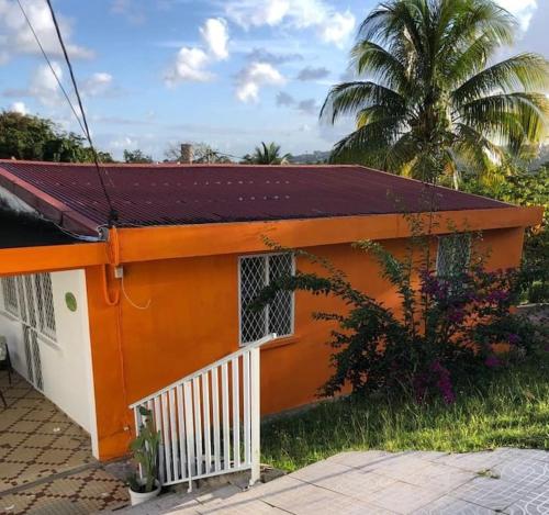 una casa blanca y naranja con una palmera en Maison chaleureuse avec terrasse et parking privé en Le Lamentin
