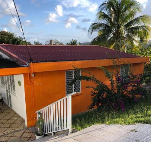 an orange and white house with a palm tree at Villa VICTORIA in Le Lamentin