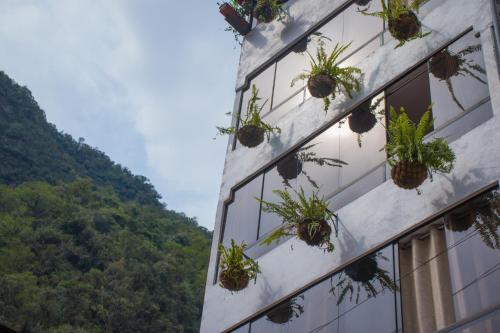 a building with potted plants on the side of it at Runas Inn Machupicchu in Machu Picchu