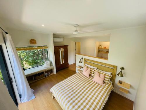 - une chambre avec un lit doté d'oreillers roses et d'une fenêtre dans l'établissement Treehouse Hideaway, à Opua
