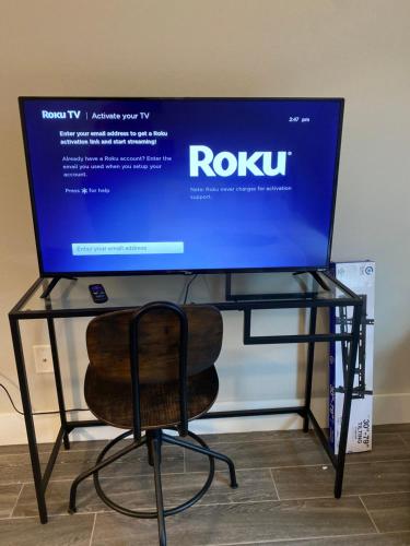 a tv sitting on a glass table with a chair at Private entrance apartment in Bentonville