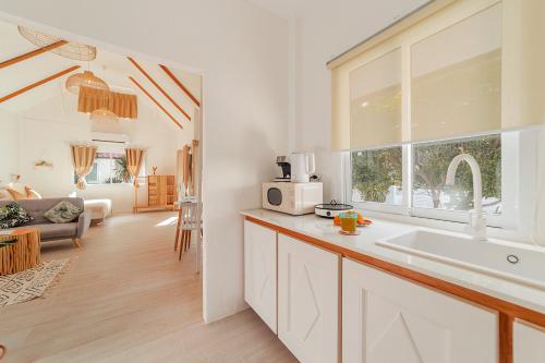 a white kitchen with a sink and a window at Sunset Lover Beach Residence in Thongsala