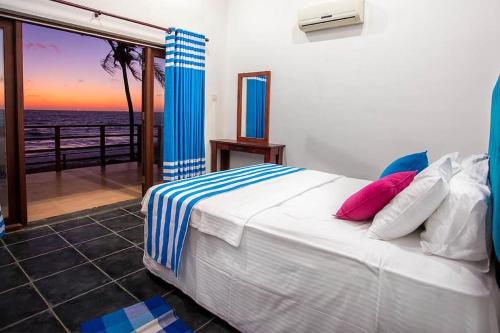 a bedroom with a bed with a view of the ocean at Reef Bungalow Private Villa, 6 bedrooms in Bopitiya