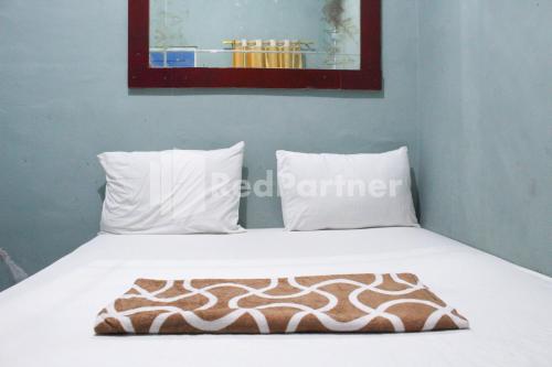 a bed with white sheets and pillows in a room at Snow White Residence near Grogol Mitra RedDoorz in Jakarta