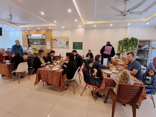 grupa ludzi siedzących przy stolikach w restauracji w obiekcie Cat Ba Green Hotel w mieście Cát Bà