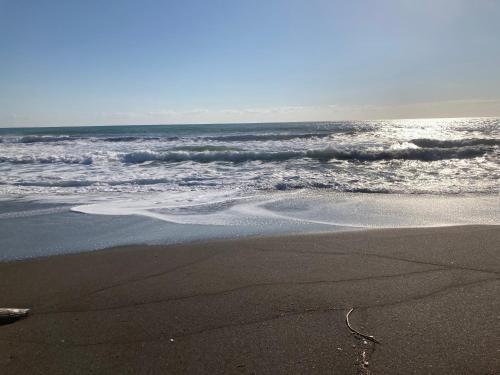 a sandy beach with waves and the ocean at ocean villa mint 満天の星空とオーシャンビューで心満たす一棟まるごと貸切別荘 南房総千倉 in Chikura