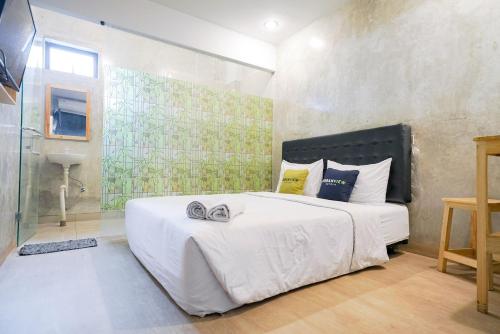 丹格朗的住宿－Urbanview Hotel Syariah De Umbrella Ciputat，卧室配有带鞋的大型白色床