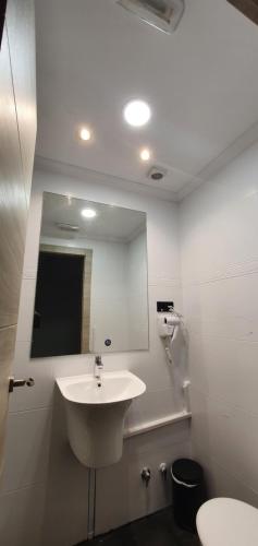 bagno bianco con lavandino e specchio di CH Otello Rooms I - Madrid a Madrid