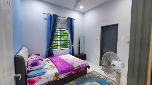 テメルローにあるHomestay D Paya Jauhの小さなベッドルーム(ベッド1台、ファン付)