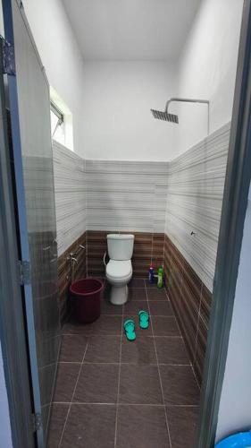 a bathroom with a toilet and a tiled floor at Homestay D Paya Jauh in Temerloh