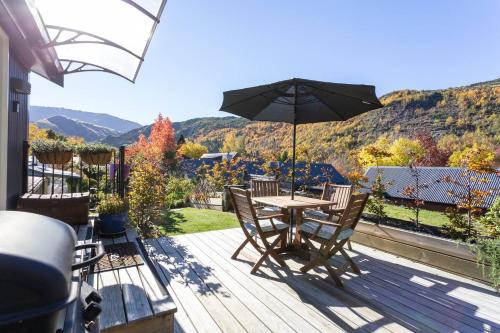a patio with a table and chairs and an umbrella at Elevated two bedroom apartment in Arrowtown