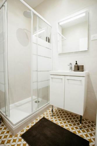 a white bathroom with a shower and a sink at Cosy Appart hôtel Next to Paris in Montreuil