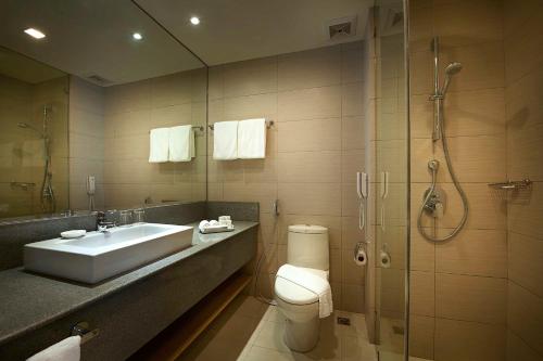 y baño con aseo, lavabo y ducha. en Berjaya Makati Hotel en Manila