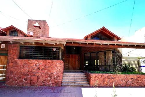 ein rotes Backsteinhaus mit einer Steinmauer in der Unterkunft Gran casa corazón de Mendoza in Mendoza
