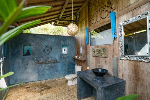 a bathroom with a toilet and a table and a mirror at Hati Padi Cottages in Ubud