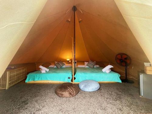 Zelt mit grünem Bett in einem Zimmer in der Unterkunft Rembulan Escape - beachfront bell tent (no 1) in Kampung Penarik