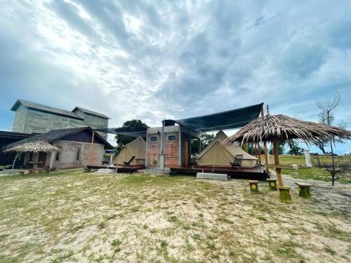 un bâtiment avec une cour herbeuse devant lui dans l'établissement Rembulan Escape - beachfront bell tent (no 1), à Kampung Penarik