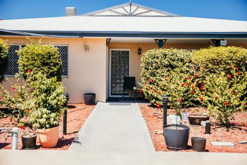 una pasarela frente a una casa con árboles y flores en Outback Motel Mt Isa, en Mount Isa