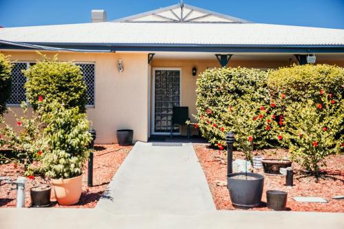a walkway in front of a house with trees and flowers at Outback Motel Mt Isa in Mount Isa