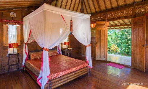 1 dormitorio con 1 cama con dosel en Hati Padi Cottages en Ubud