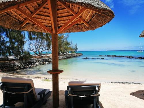 two chairs under an umbrella on a beach at Wonders Beach Boutique Hotel in Mont Choisy