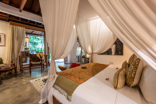 a bedroom with a white bed with curtains at Baby Melon Villas in Seminyak