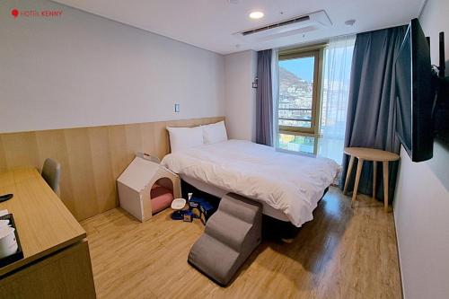 a small room with a bed and a window at Hotel Kenny Yeosu in Yeosu