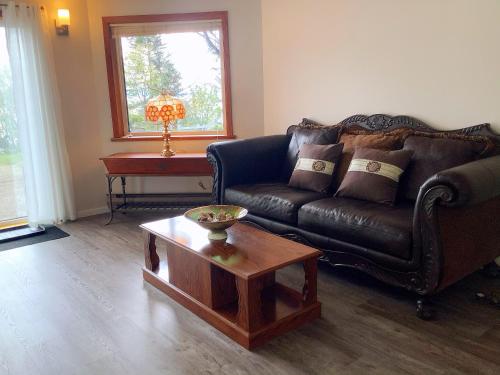 a living room with a leather couch and a coffee table at Ocean's Edge Suite in Campbell River